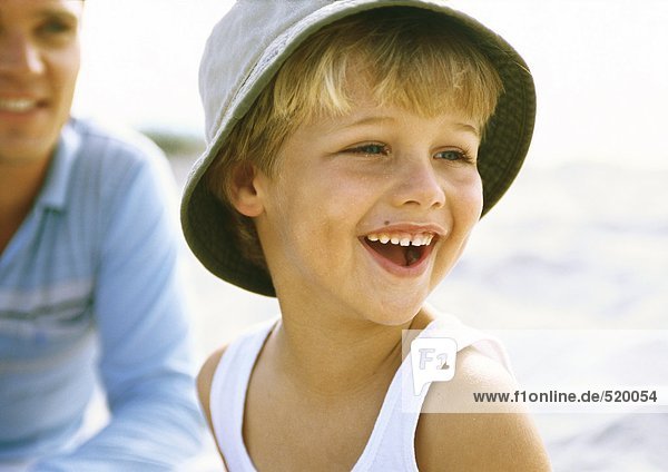 Junge mit Hut am Strand mit Vater