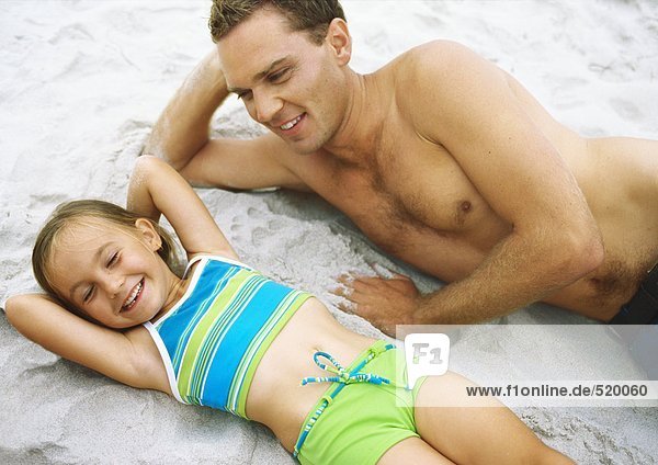 Mädchen und Vater am Strand liegend