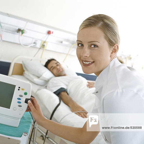 Krankenschwester überprüft Patientenmonitor