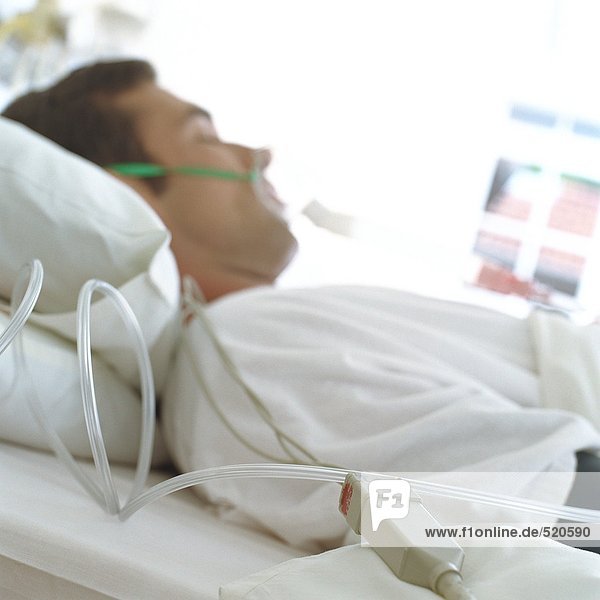 Patient im Krankenhausbett mit Maske