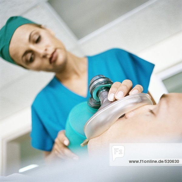 Ärztin hält Sauerstoffmaske über das Gesicht des Patienten