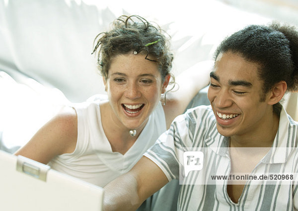 Junges Paar schaut auf Laptop  lächelnd
