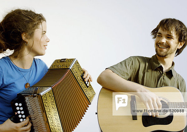 Young man playing guitar  young woman playing accordion