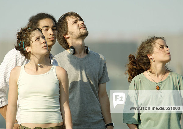 Vier junge Freunde stehen und schauen in den Himmel.