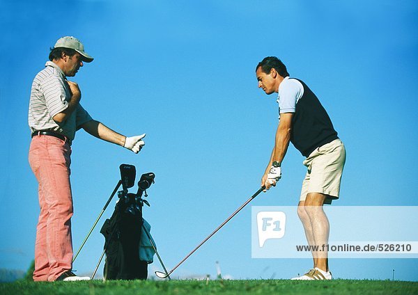 Mann nimmt Unterricht bei einem Golflehrer