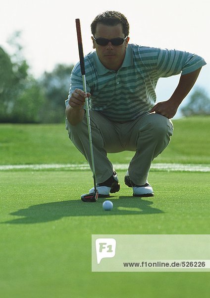 Golfer squatting on green  front view