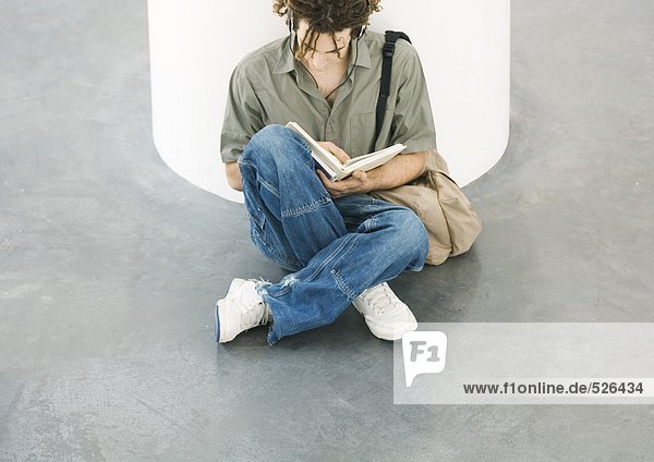 Young man sitting on floor  reading