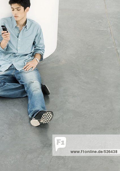 Young man sitting on floor looking at cell phone