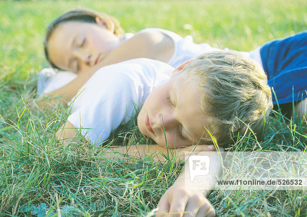 Junge und Mädchen schlafen im Gras