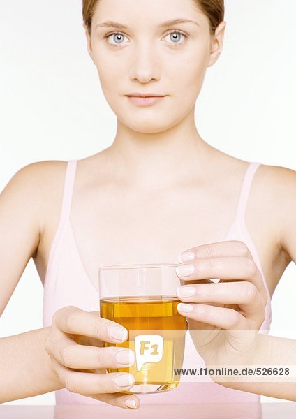 Junge Frau hält ein Glas Apfelsaft in der Hand