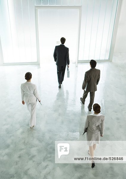 Four executives walking across lobby toward exit