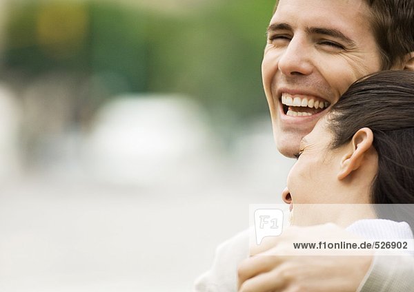 Junges Paar lacht  Frau ruht Kopf auf der Schulter des Mannes