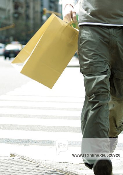 Junger Mann läuft mit Einkaufstasche