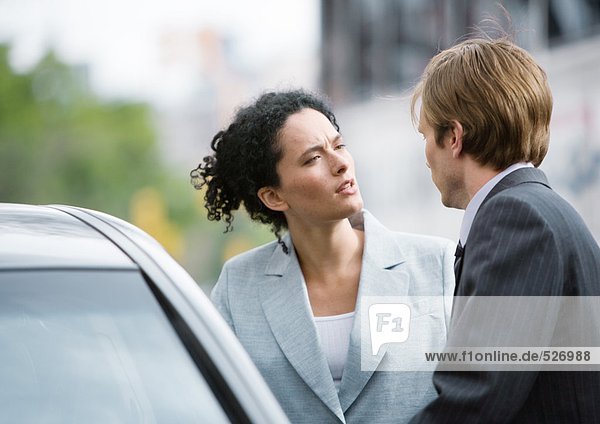 Geschäftsfrau und Mann sprechen neben dem Auto