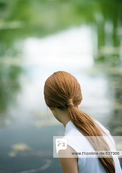 Mädchen schaut auf den Teich  Rückansicht