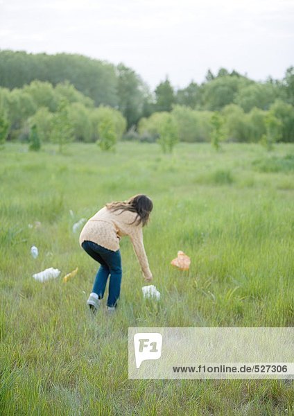 Frau beim Aufnehmen von Plastiktüten im Feld