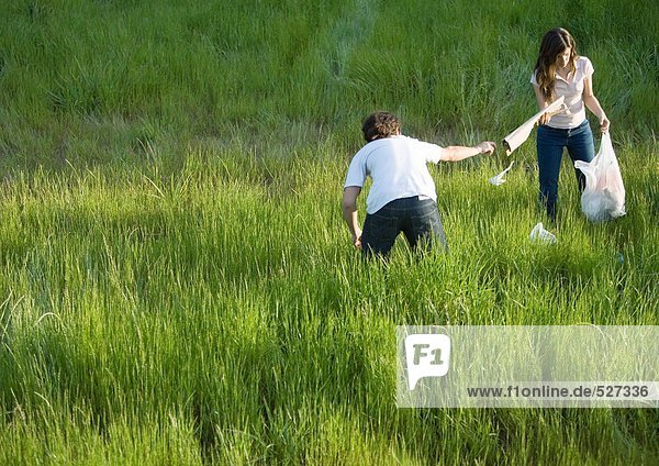 Young couple picking up litter in field