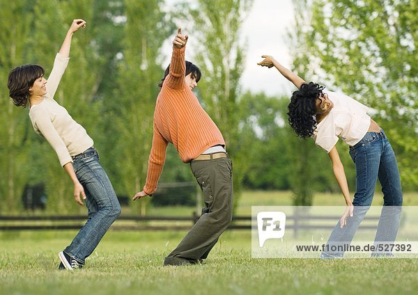 Three friends dancing in a line outdoors