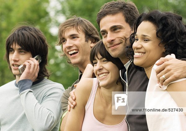 Group of young friends smiling  one using cell phone