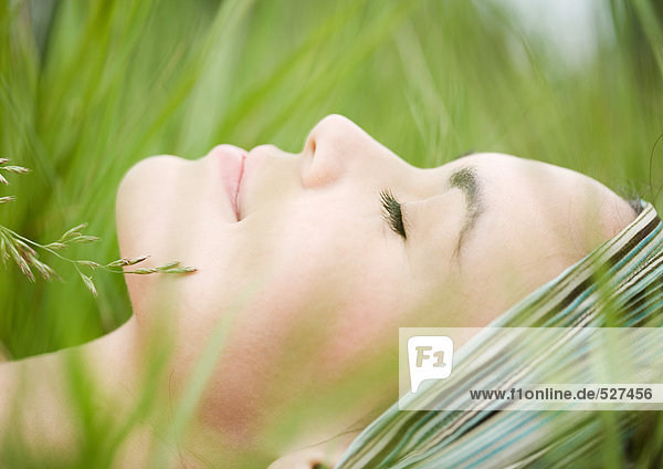Junge Frau im Gras liegend  Nahaufnahme des Gesichts