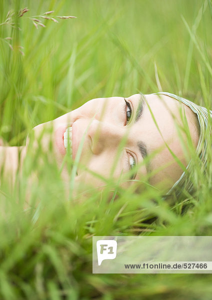 Junge Frau im Gras liegend  Nahaufnahme des Gesichts