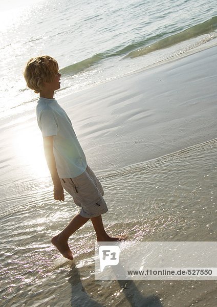 Boy walking in surf at beach