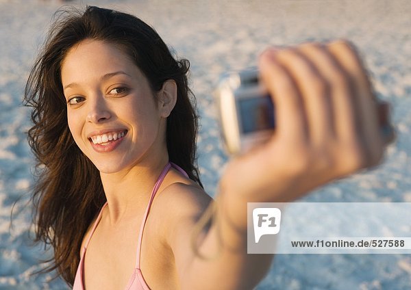 Junge Frau fotografiert sich selbst am Strand