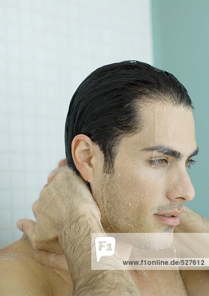 Mann mit Händen hinter dem Hals in der Dusche