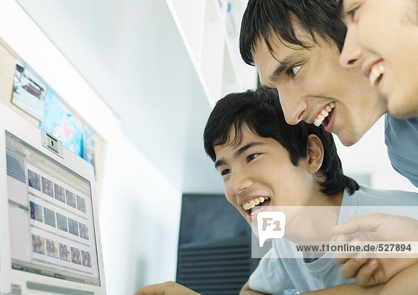 Three young friends looking at computer screen