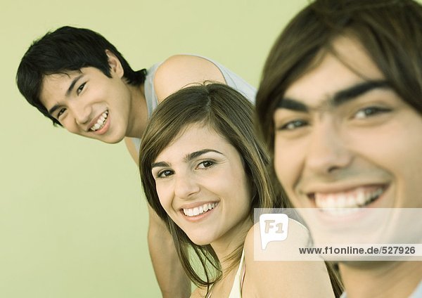 Drei junge erwachsene Freunde lächeln