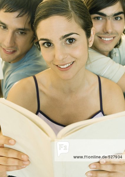 Young woman holding book  two friends in background