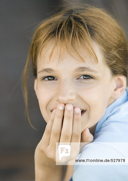 Girl covering mouth looking at camera  smiling  portrait  close-up