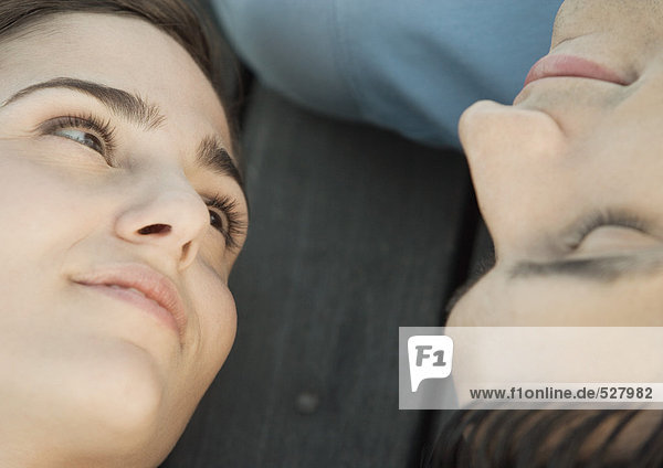 Young woman reclining on the ground  looking at her boyfriend upside down  smiling  portrait  extreme close-up