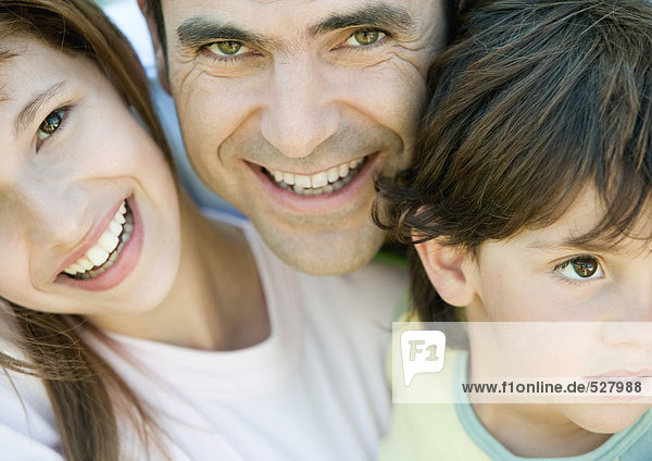 Vater mit zwei Kindern  Junge schaut weg  Vater und Tochter lächeln und schauen in die Kamera  Porträt  Nahaufnahme