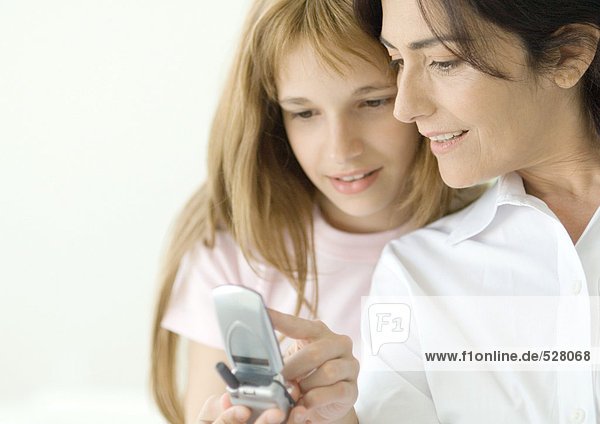 Girl looking at cell phone with mature woman