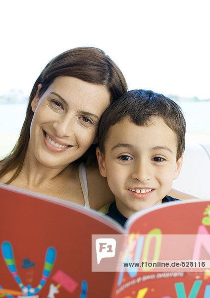 Mutter und Sohn mit Buch  lächelnd vor der Kamera
