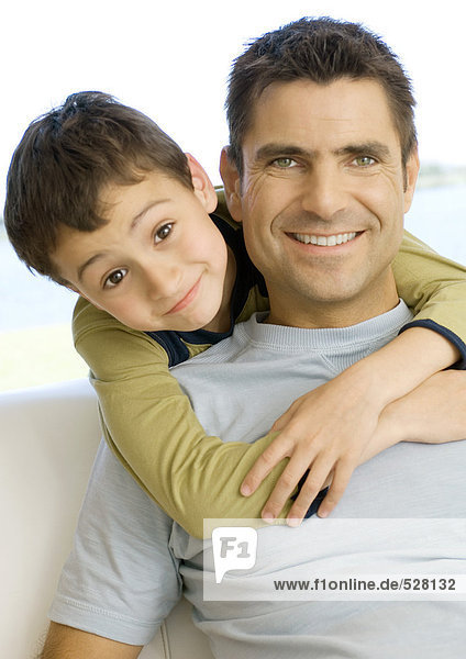 Junge umarmt Vater von hinten  Portrait