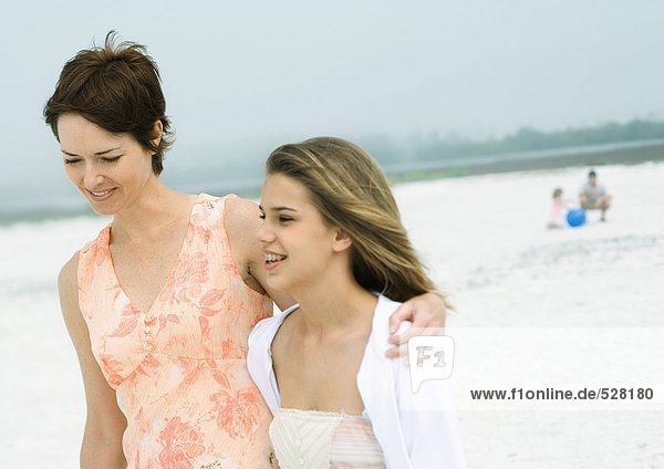 Frau geht mit Teenager-Tochter am Strand spazieren