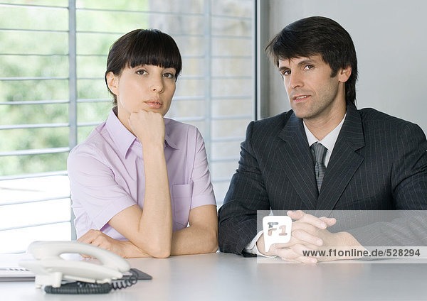 Two business people next to phone in office