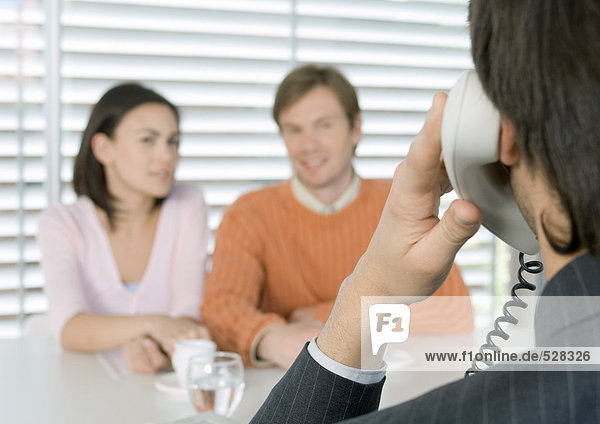 Businessman using phone while couple waits