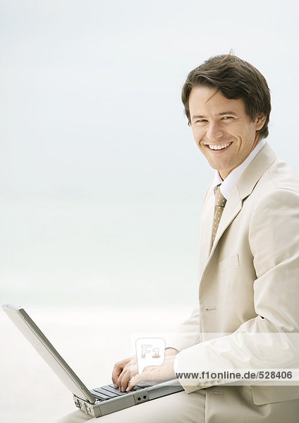 Geschäftsmann mit Laptop  lächelnd vor der Kamera
