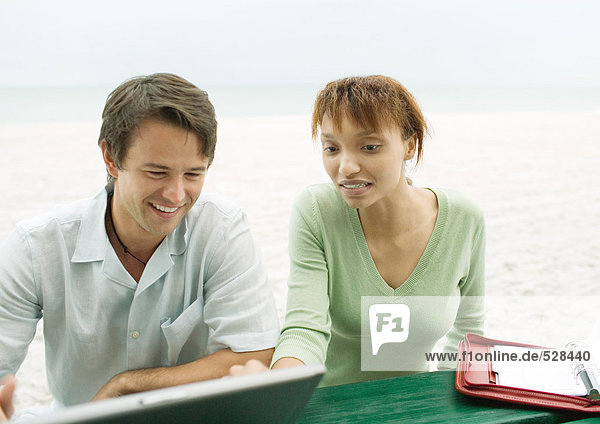 Mann und Frau  mit Laptop am Strand