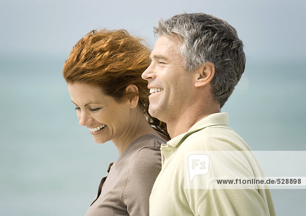 Mature couple smiling by seaside