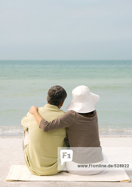 Paar am Strand sitzend  Blick aufs Meer  Rückansicht
