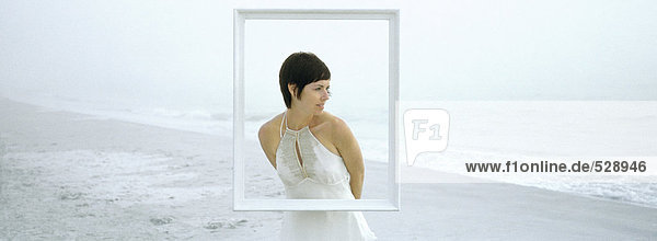 Woman standing on beach  behind frame