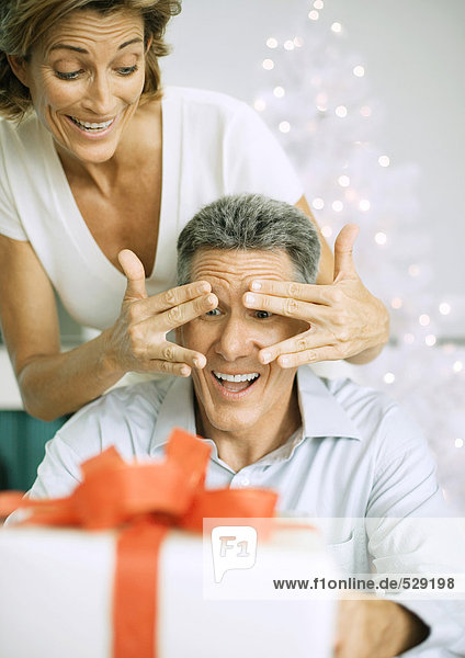 Frau überrascht Mann mit Weihnachtsgeschenk
