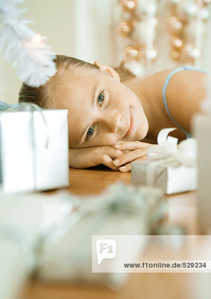 Mädchen auf dem Boden liegend neben Weihnachtsgeschenken