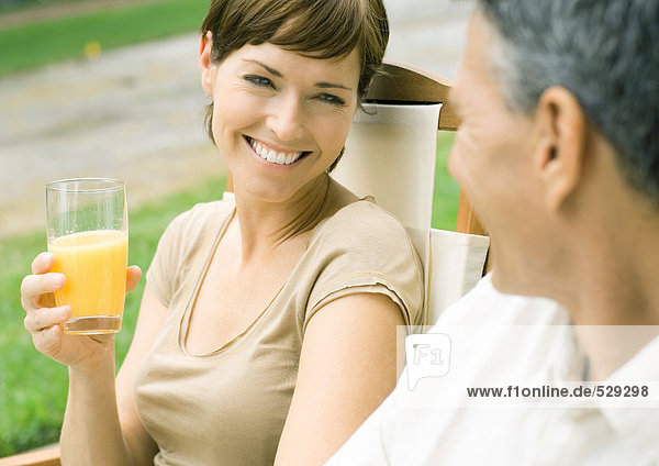 Frau hält ein Glas Orangensaft  schaut den Mann an