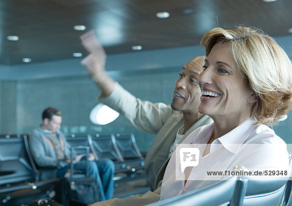 Mann und Frau sitzen in der Flughafenlounge  lachend