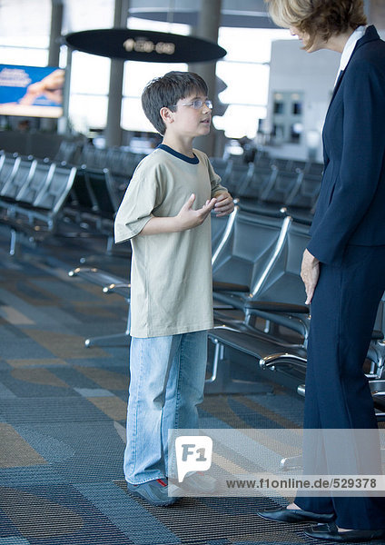 Boy speaking to airline attendant in airport lounge